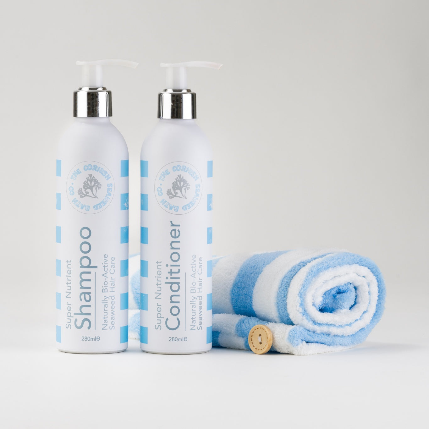 Assorted bathing bars with skincare ingredients and a towel on a neutral background